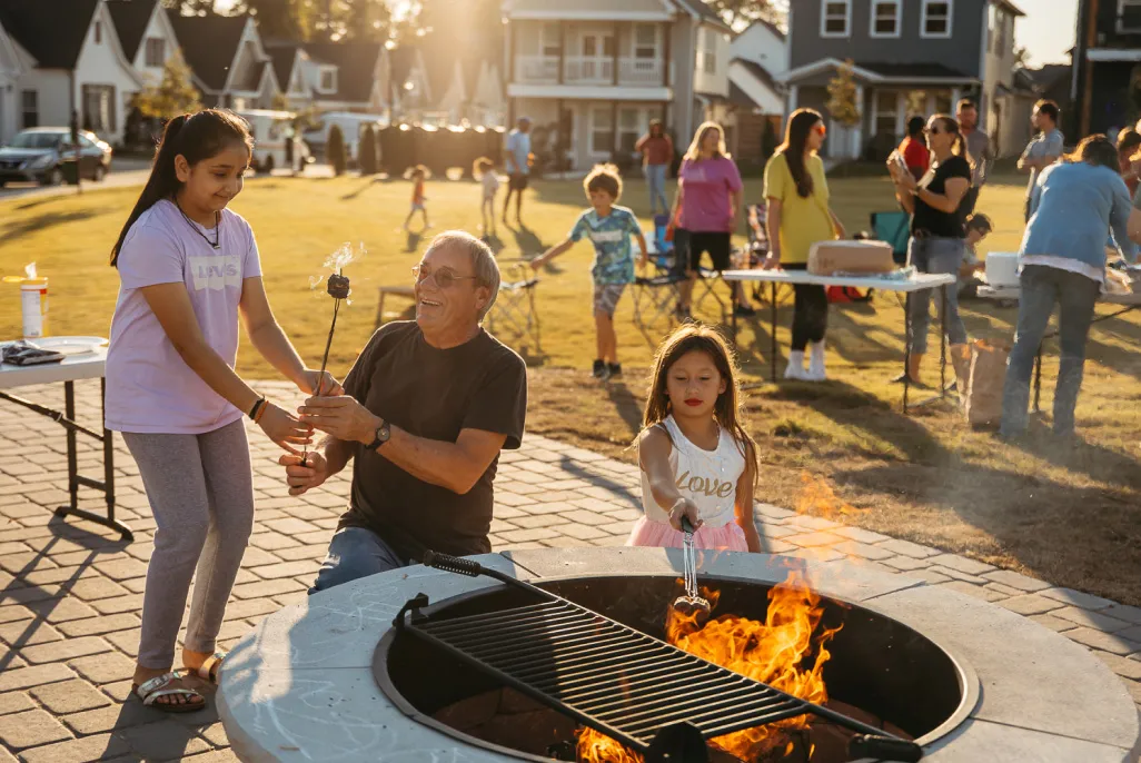 Families gathered around a fire pit at a GreenTech Homes neighborhood at golden hour